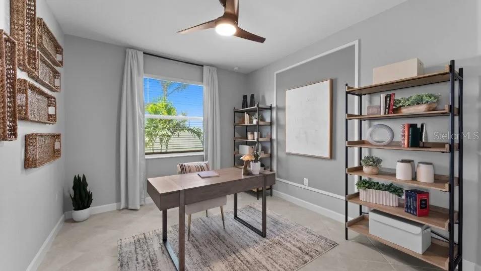 A home office features a desk, two shelving units, wall decor, and a window with curtains — 8462 WATER LILY COURT, ENGLEWOOD, FL