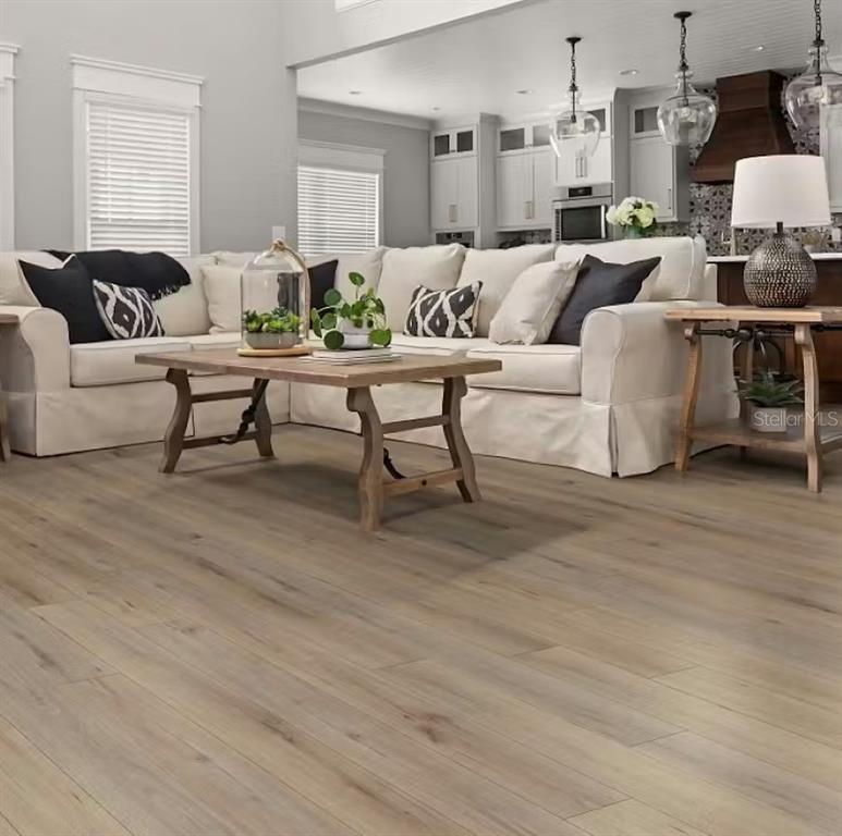 A living room with light wood floors, a beige sectional sofa, and an open kitchen — 1536 OTTER WOODS LANE, AUBURNDALE, FL