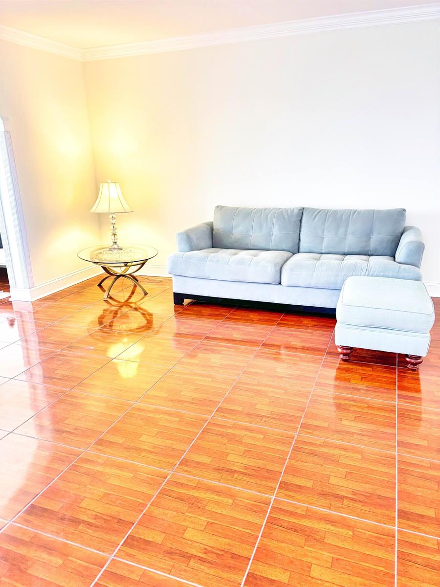 A living room features a light blue sofa, a matching ottoman, and a glass side table — 14671 Bonaire Boulevard Apt 505, Delray Beach FL 33446, DELRAY BEACH, FL