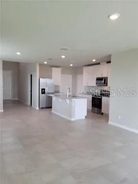 A modern kitchen features white cabinetry, stainless steel appliances, and a central island — 3085 BELLA VISTA DRIVE, DAVENPORT, FL