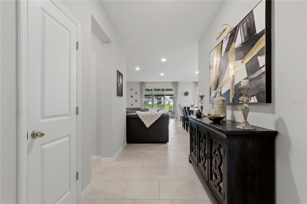 A hallway with light tile flooring leads to a living area with a view outside — 11316 SPOONBILL FLOCK WAY, SAN ANTONIO, FL