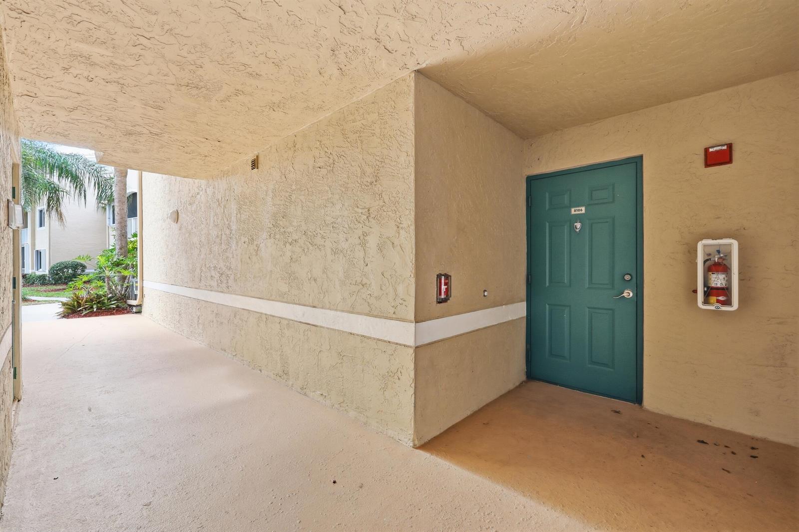 An exterior view of a teal apartment door with a fire extinguisher nearby — 278 Village Boulevard # 8106, Tequesta FL 33469, TEQUESTA, FL