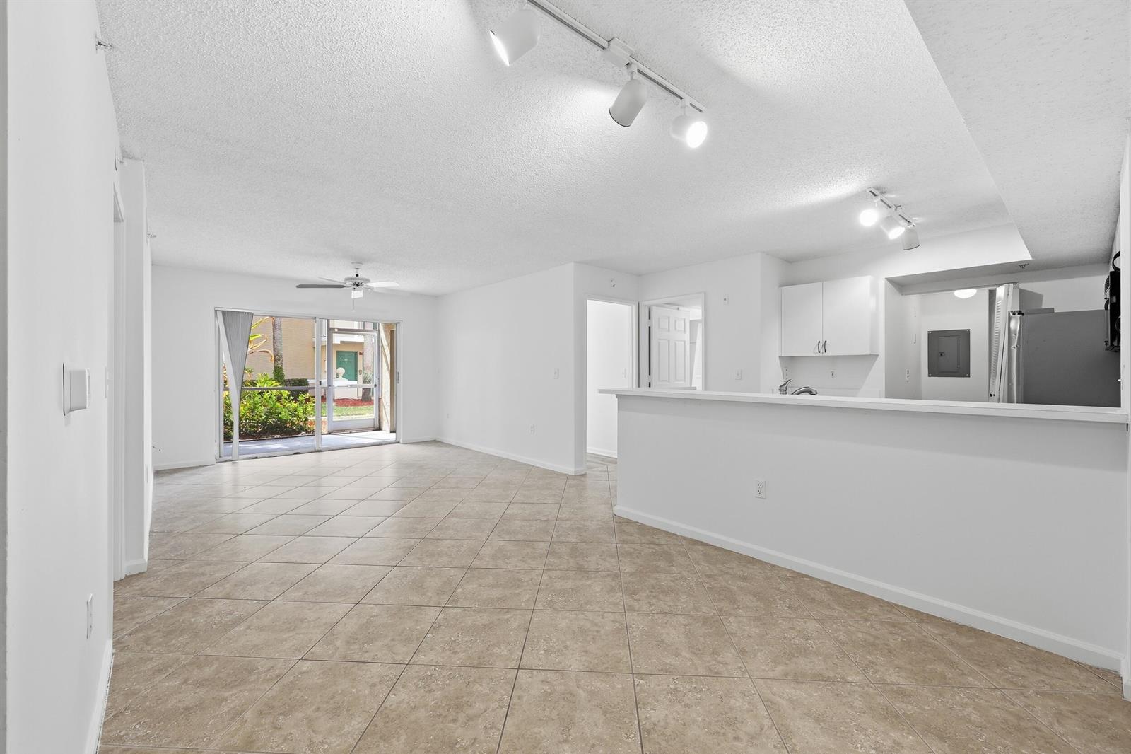 An open-concept living area with tile flooring, a kitchen breakfast bar, and sliding glass doors — 278 Village Boulevard # 8106, Tequesta FL 33469, TEQUESTA, FL