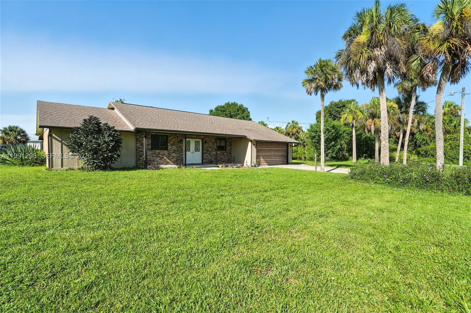 A single-story house with a brick facade, brown roof, and attached garage sits on grass — 5006 pike ln, La Belle FL 33935, LA BELLE, FL