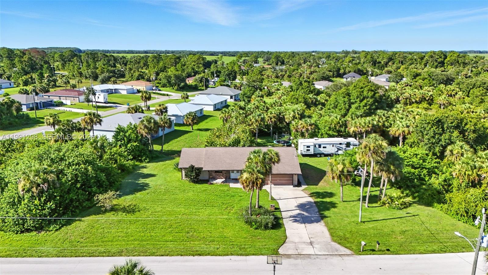 An aerial view shows a single-story house with a driveway, palm trees, and an RV — 5006 pike ln, La Belle FL 33935, LA BELLE, FL