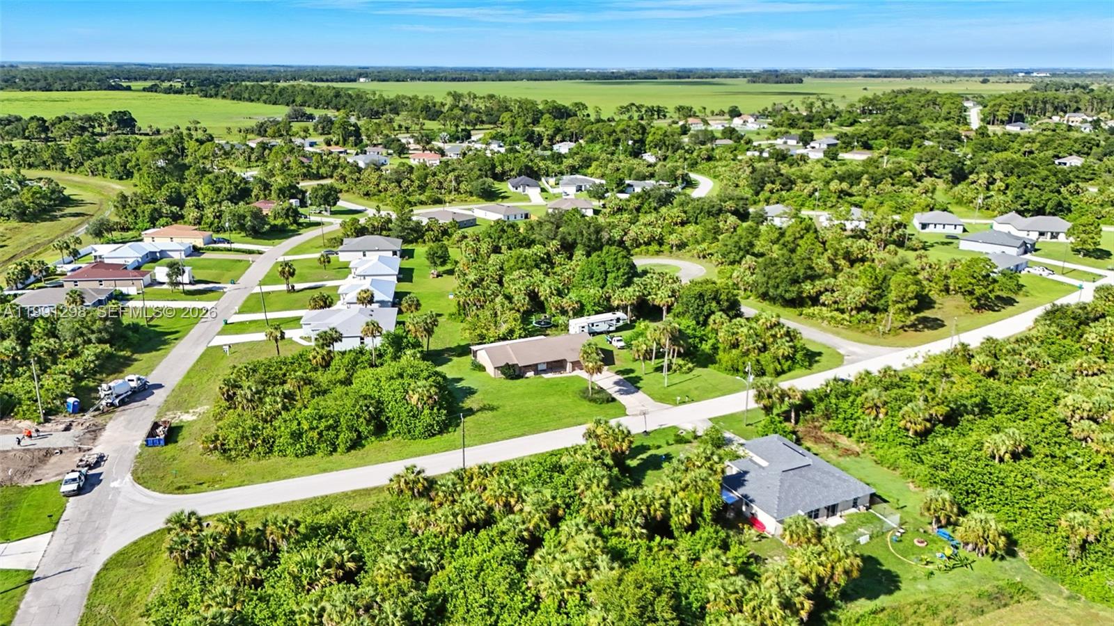 An aerial view shows a residential neighborhood with houses surrounded by trees and green fields — 5006 pike ln, La Belle FL 33935, LA BELLE, FL
