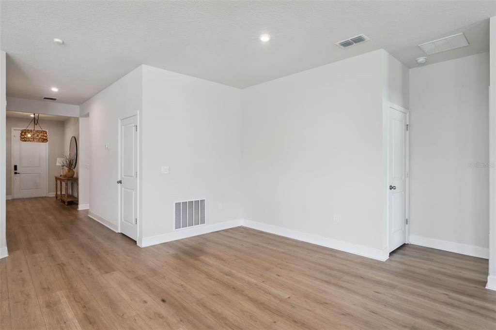 An interior view showing a hallway, two closed doors, and light wood-look flooring — 455 WINTER SOLSTICE LANE, MOUNT DORA, FL
