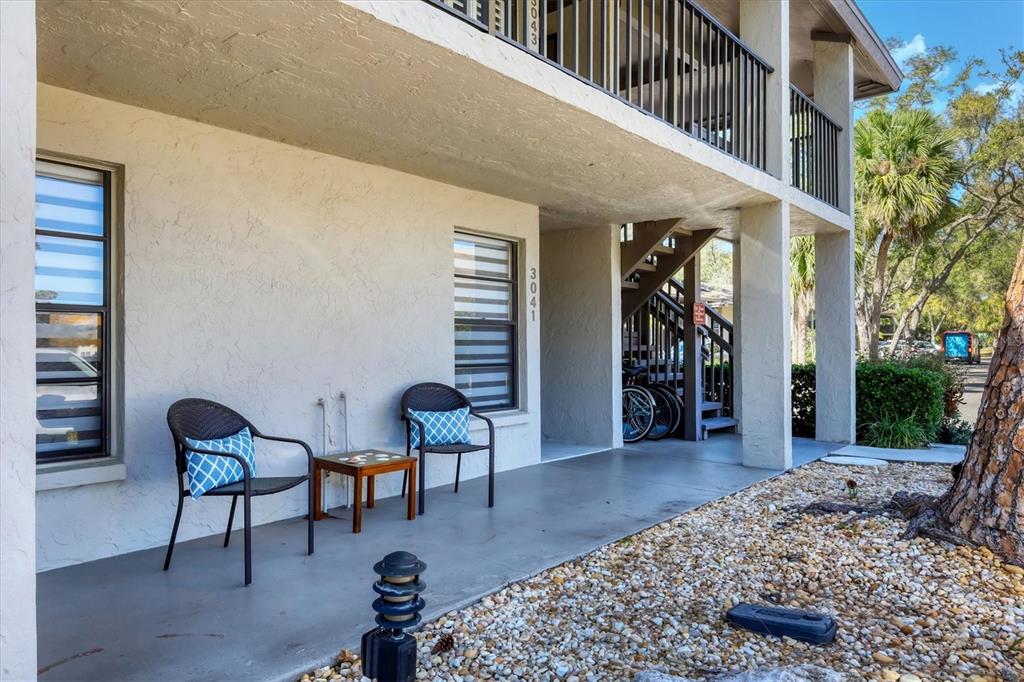 A ground-level patio features two chairs, a small table, and stairs leading to upper units — 3041 QUAIL HOLLOW UNIT 27, SARASOTA, FL