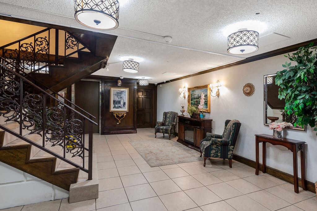 A tiled lobby features a wooden staircase with ornate iron railings and two armchairs — 3680 Inverrary Drive # 1v, Lauderhill FL 33319, LAUDERHILL, FL