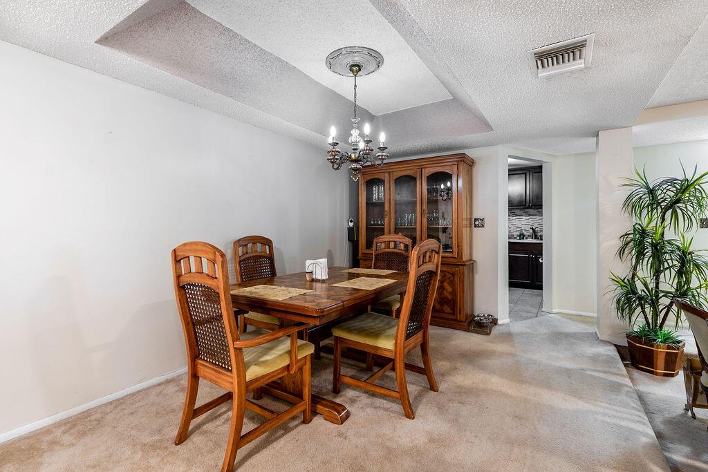 A dining room features a wooden table and chairs, a hutch, and carpeted flooring — 3680 Inverrary Drive # 1v, Lauderhill FL 33319, LAUDERHILL, FL