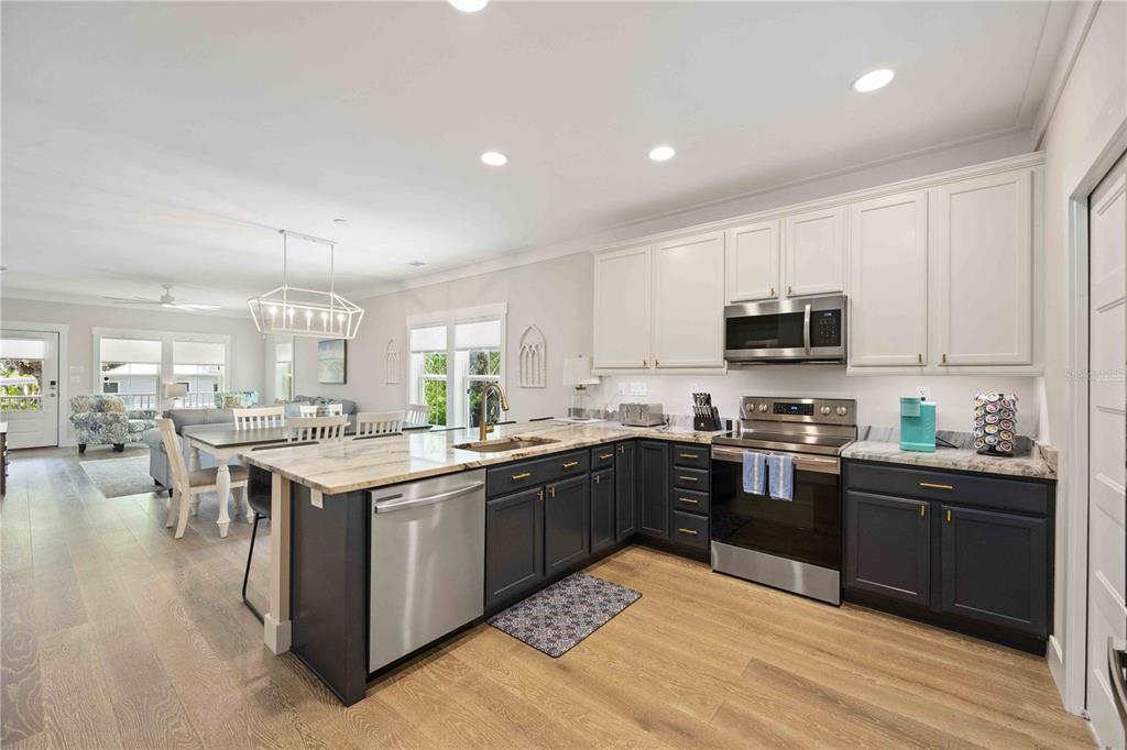 A kitchen with two-toned cabinets, stainless steel appliances, and an island with a stone countertop — 1623 8TH AVENUE W, BRADENTON, FL
