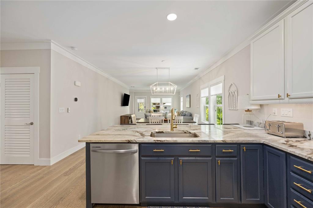 A kitchen with dark blue lower cabinets and a marble countertop overlooks a dining area — 1623 8TH AVENUE W, BRADENTON, FL