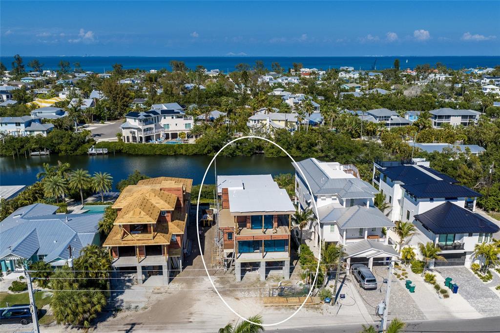 An aerial view shows a multi-story house under construction situated along a waterfront canal — 406 N SHORE DRIVE, ANNA MARIA, FL