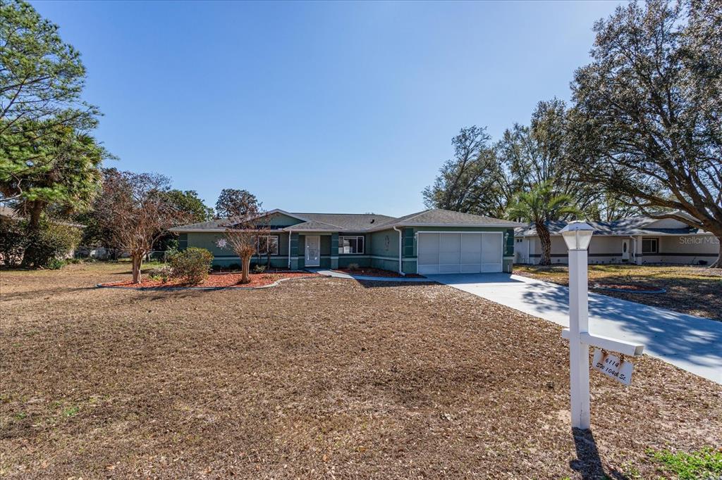 A single-story house with a green exterior, a two-car garage, and a large front yard — 6114 SW 104TH STREET, OCALA, FL