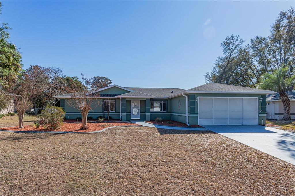 A single-story green house with a two-car garage and a front walkway — 6114 SW 104TH STREET, OCALA, FL