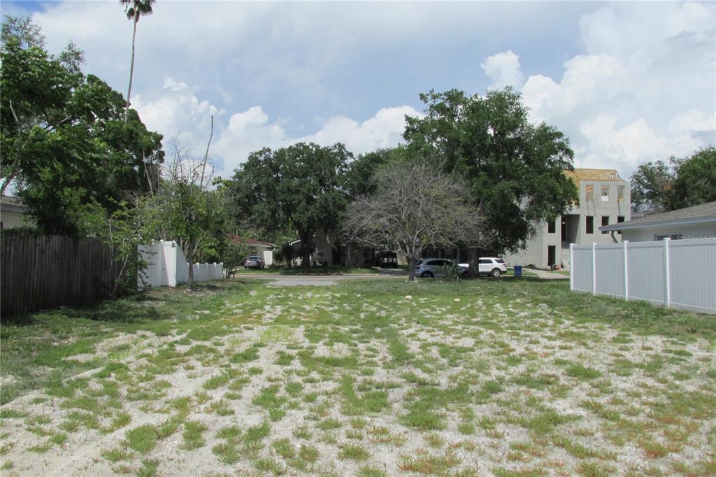A vacant, grassy, and gravel-covered residential lot sits between two white vinyl fences — 508 E DAVIS BOULEVARD, TAMPA, FL