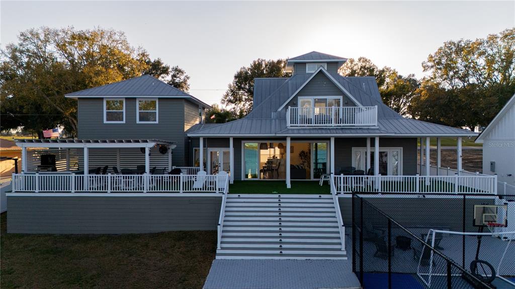 A two-story house with a large deck, stairs, and a fenced sports court — 5671 OLD BERKLEY ROAD, AUBURNDALE, FL
