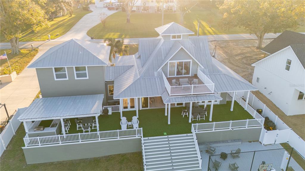 An aerial view of a multi-story house with a metal roof, balcony, and backyard patio — 5671 OLD BERKLEY ROAD, AUBURNDALE, FL