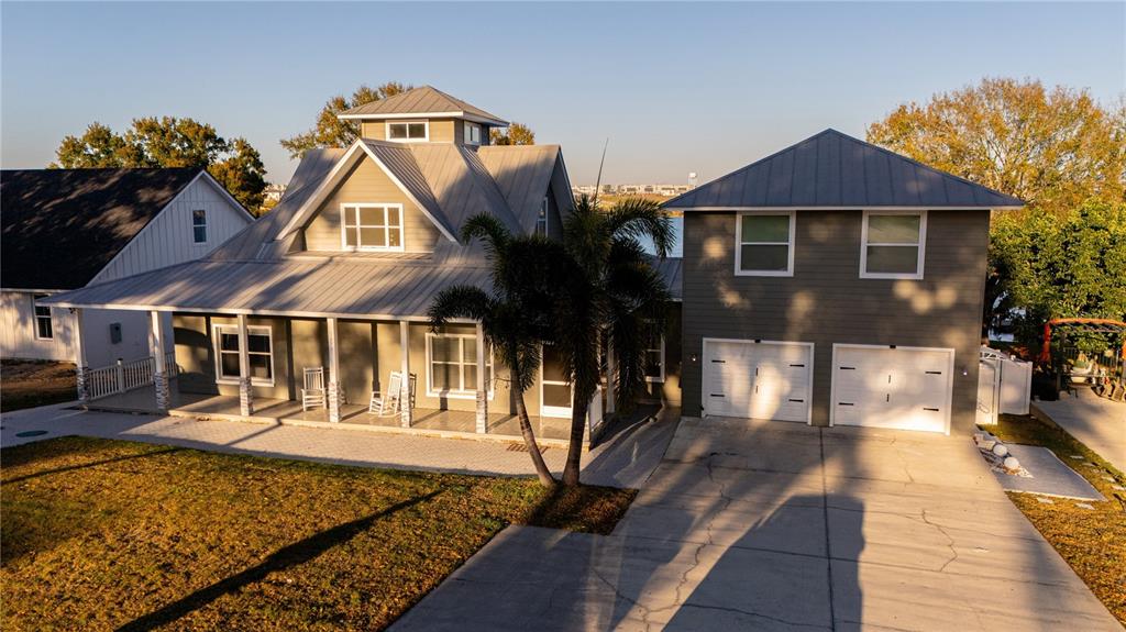 An exterior view of a two-story house with a metal roof and attached garage — 5671 OLD BERKLEY ROAD, AUBURNDALE, FL