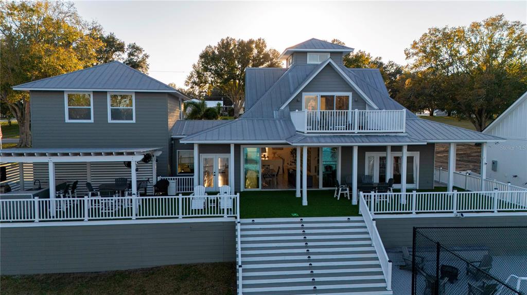 An exterior view of a multi-story gray house with a metal roof and large deck — 5671 OLD BERKLEY ROAD, AUBURNDALE, FL
