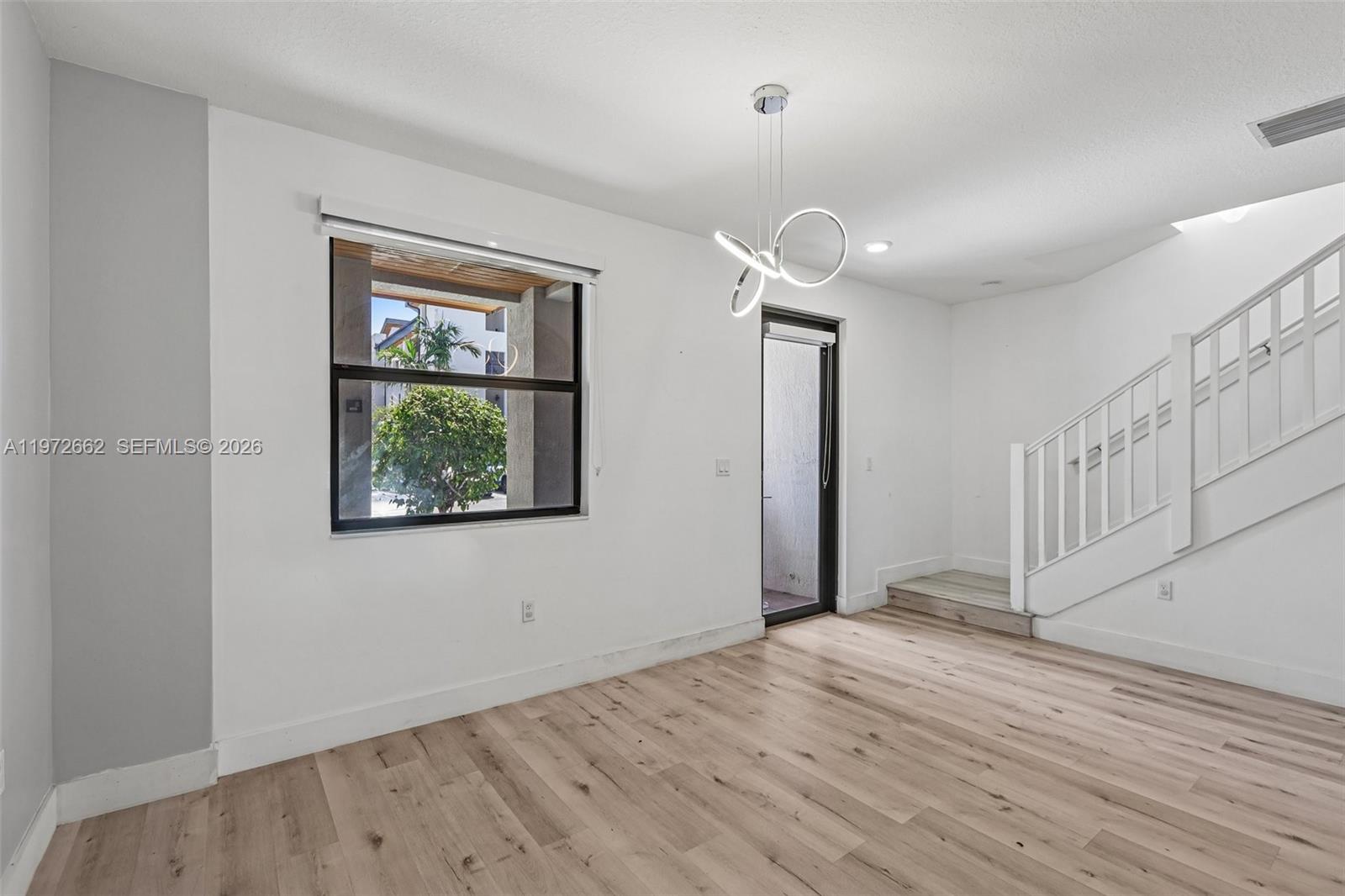 A bright room features light wood flooring, a modern chandelier, and a staircase — 10455 NW 82nd St # 4, Doral FL 33178, DORAL, FL