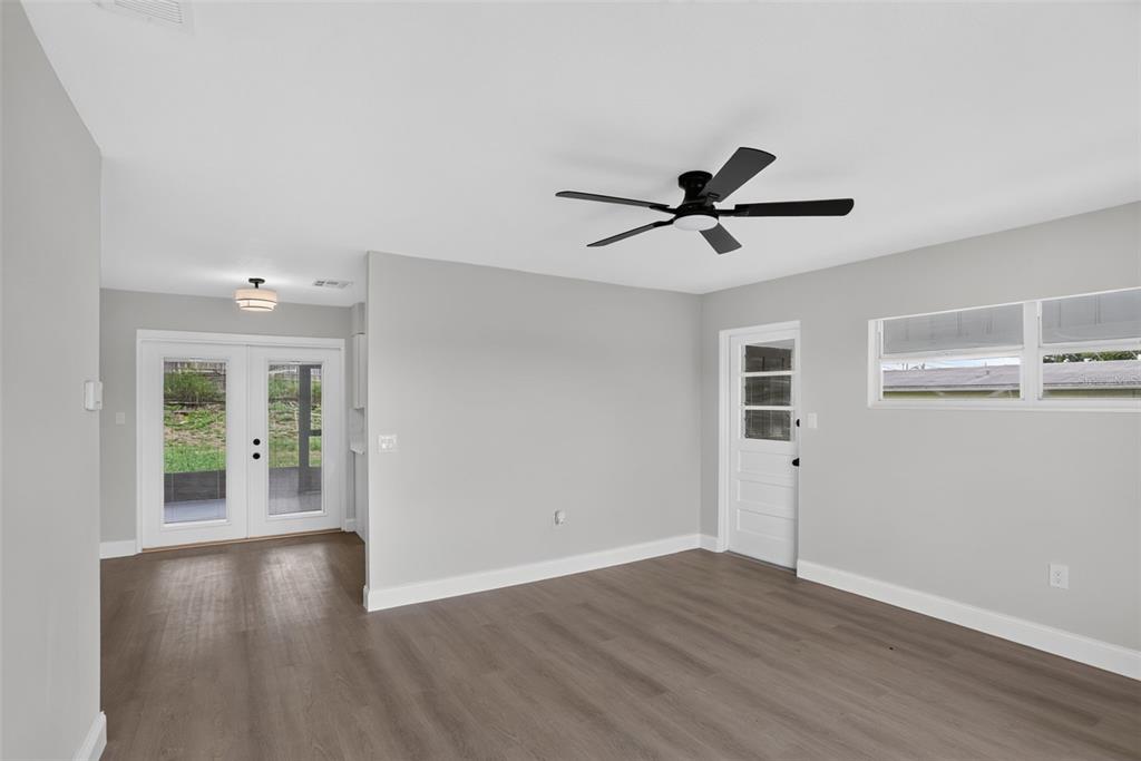 A living room with gray walls, wood-look flooring, a ceiling fan, and glass-paneled exterior doors — 3413 PARIS PLACE, ORLANDO, FL