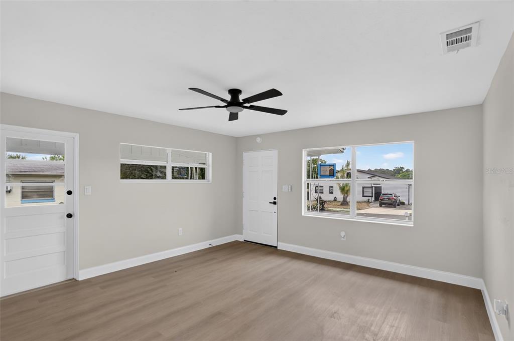 An empty room features light gray walls, wood-look flooring, a ceiling fan, and two doors — 3413 PARIS PLACE, ORLANDO, FL