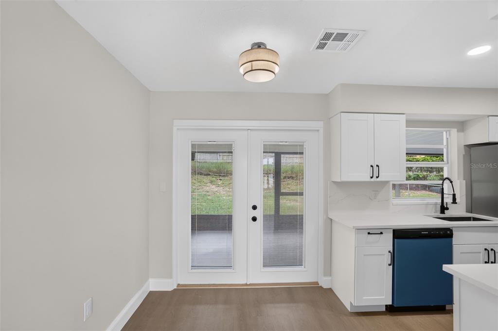 A kitchen area features white cabinets, a blue dishwasher, and glass doors leading outside — 3413 PARIS PLACE, ORLANDO, FL