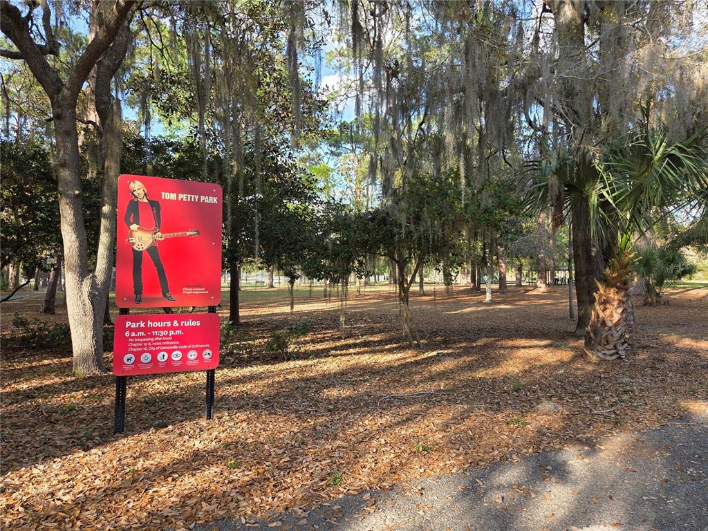 A red sign for Tom Petty Park stands in a wooded area with Spanish moss — (Parcel 3) 214 NE 13TH AVENUE, GAINESVILLE, FL