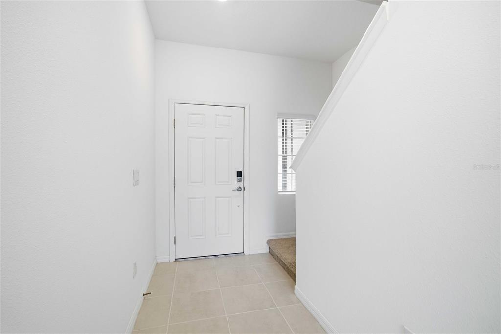 An entryway features white walls, a tiled floor, a white front door, and carpeted stairs — 11731 GLENSIDE TERRACE, PALMETTO, FL