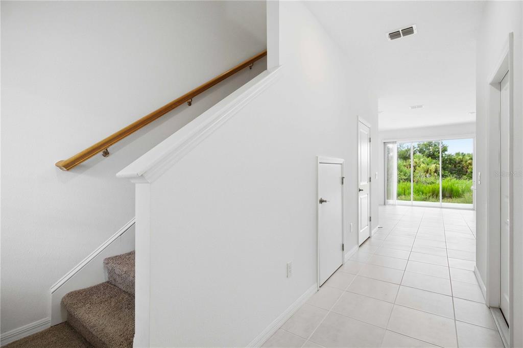 A bright entryway features a carpeted staircase with a wooden handrail and white tile flooring — 11731 GLENSIDE TERRACE, PALMETTO, FL