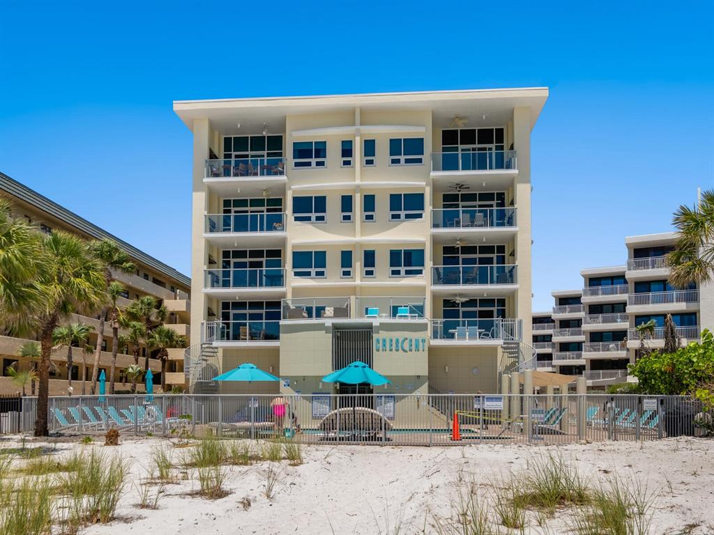 A multi-story beachfront condominium building with balconies overlooking a pool and sandy beach — 6512 MIDNIGHT PASS ROAD UNIT 303, SARASOTA, FL