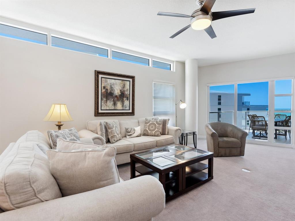 A living room features a beige sofa, a dark coffee table, and a balcony view — 6512 MIDNIGHT PASS ROAD UNIT 303, SARASOTA, FL