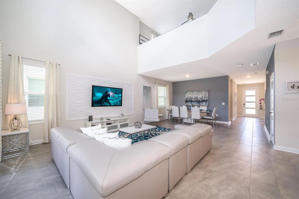 A spacious living room with high ceilings, a large sectional sofa, and an adjacent dining area — 2770 BOOKMARK DRIVE, KISSIMMEE, FL