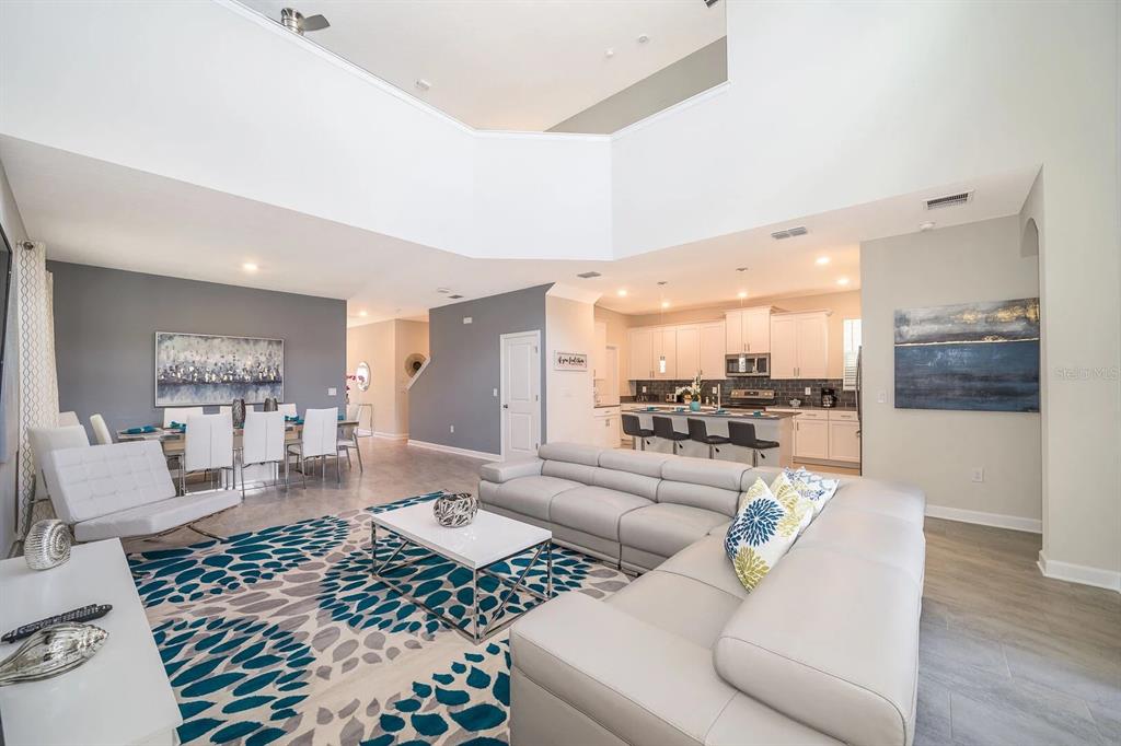 An open-concept living room and kitchen featuring a large sectional sofa and dining area — 2770 BOOKMARK DRIVE, KISSIMMEE, FL