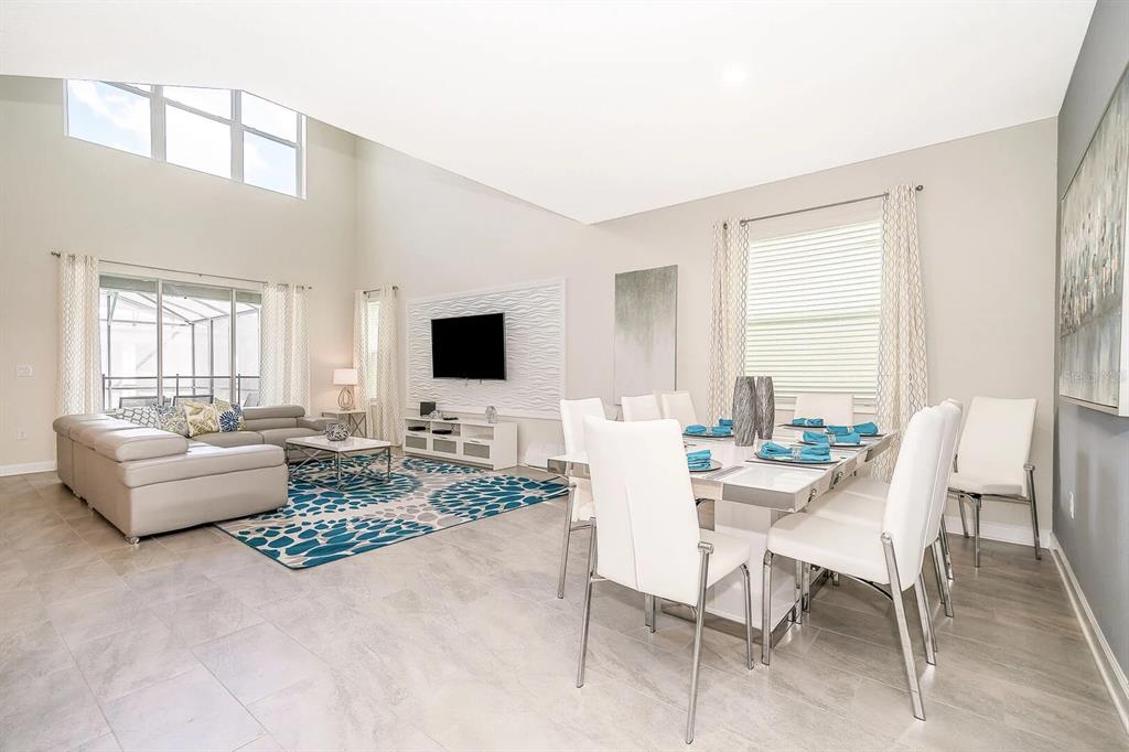 A bright, open-concept living and dining area features high ceilings, tile floors, and modern furniture — 2770 BOOKMARK DRIVE, KISSIMMEE, FL