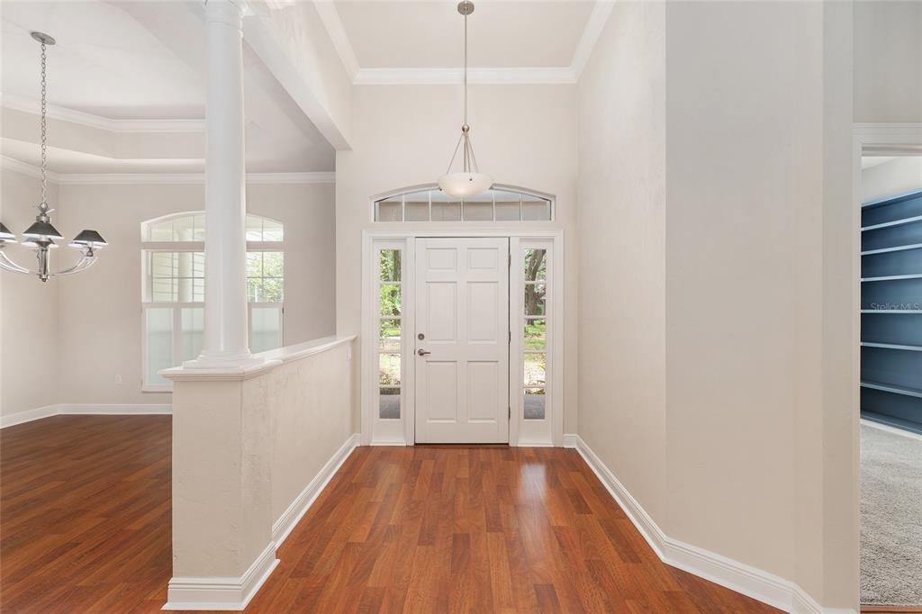 An entryway features hardwood floors, a white front door with sidelights, and a decorative column — 10511 SW 17TH PLACE, GAINESVILLE, FL