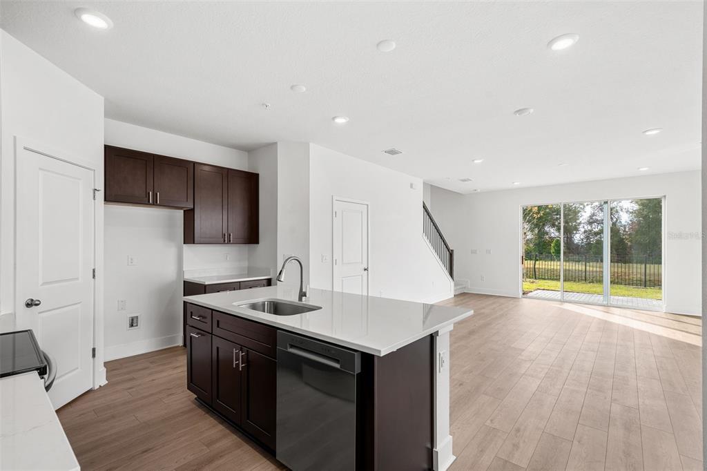 A kitchen with dark cabinets and a white island overlooks an open living area — 2458 MAGNOLIA RESERVE ROAD, OCOEE, FL