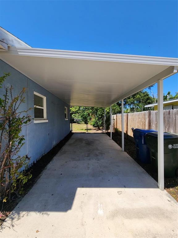 A concrete driveway is covered by a white metal carport attached to a blue house — 1608 EDNA AVENUE, LARGO, FL