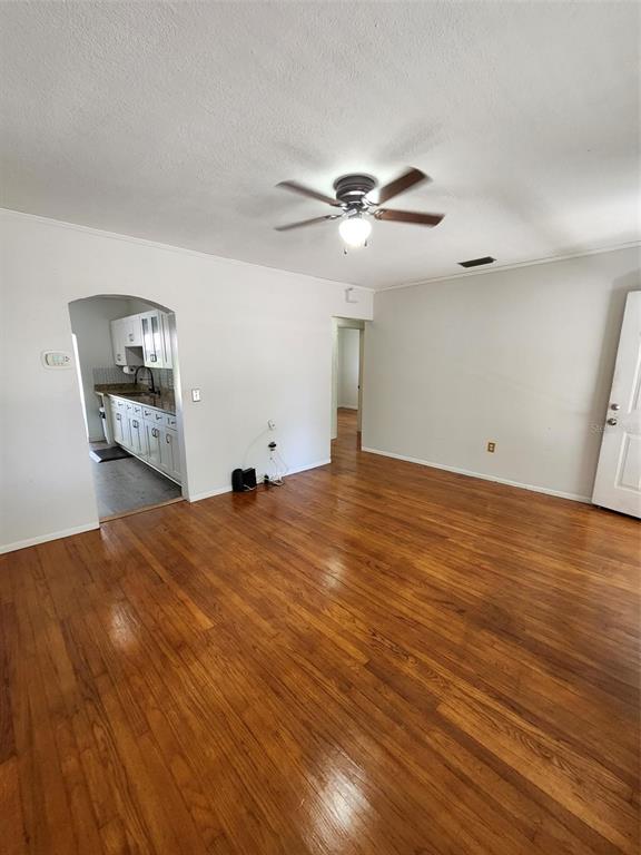 A living room with hardwood floors, a ceiling fan, and an arched doorway to a kitchen — 1608 EDNA AVENUE, LARGO, FL