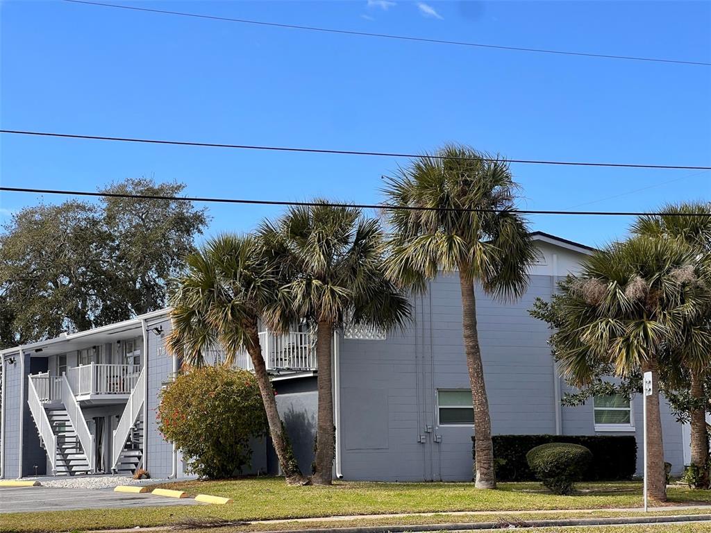 A two-story apartment building with gray siding, white railings, and several palm trees — 1710 S WASHINGTON AVENUE UNIT 14, TITUSVILLE, FL