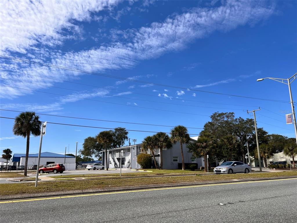 A two-story apartment building with palm trees and parked cars under a blue sky — 1710 S WASHINGTON AVENUE UNIT 14, TITUSVILLE, FL