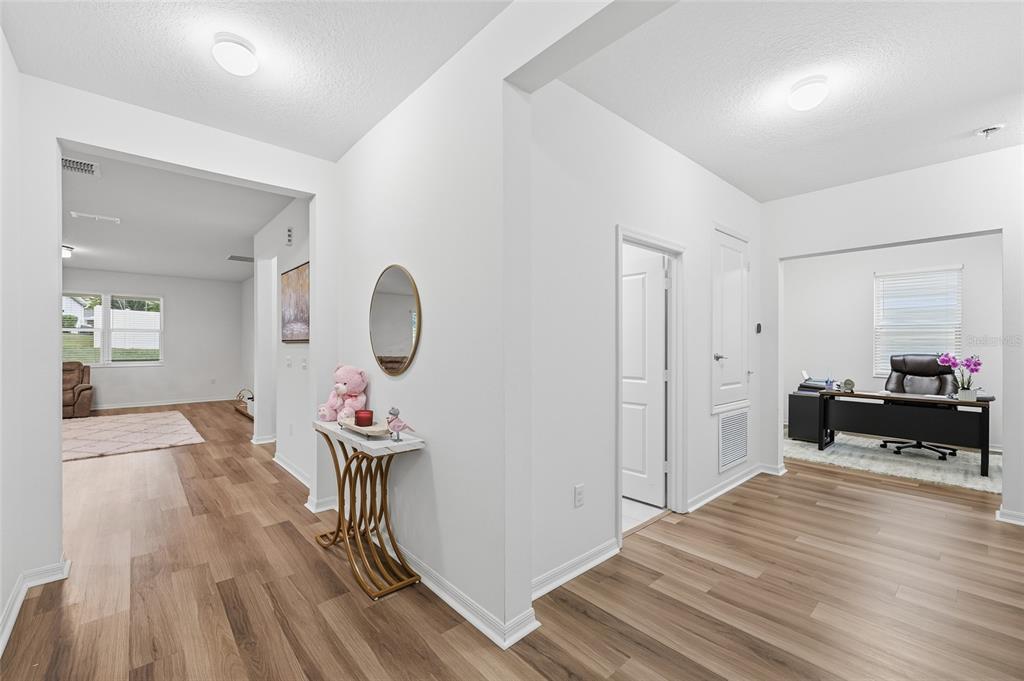 A bright entryway with wood-look flooring leads to a living area and a home office — 2081 MALBEC COURT, MINNEOLA, FL