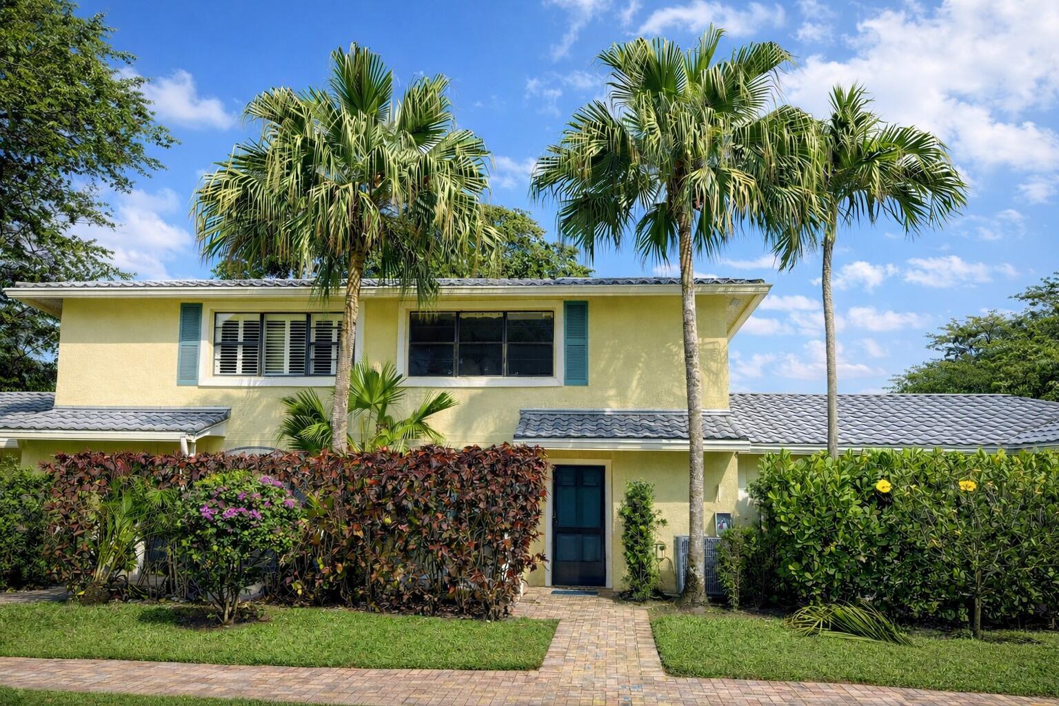 A two-story yellow house with a tiled roof, palm trees, and a brick walkway — 4 Westgate Lane # 4c, Boynton Beach FL 33436, BOYNTON BEACH, FL