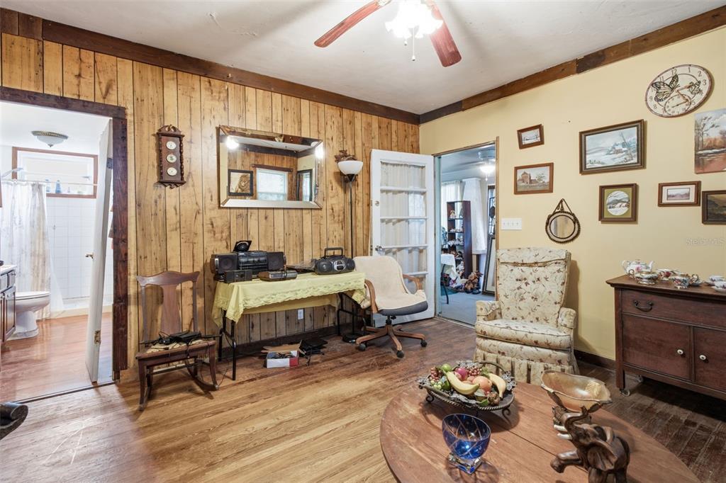 A living room features wood-paneled walls, a wooden coffee table, and a floral armchair — 1413 E NEW YORK AVENUE, DELAND, FL