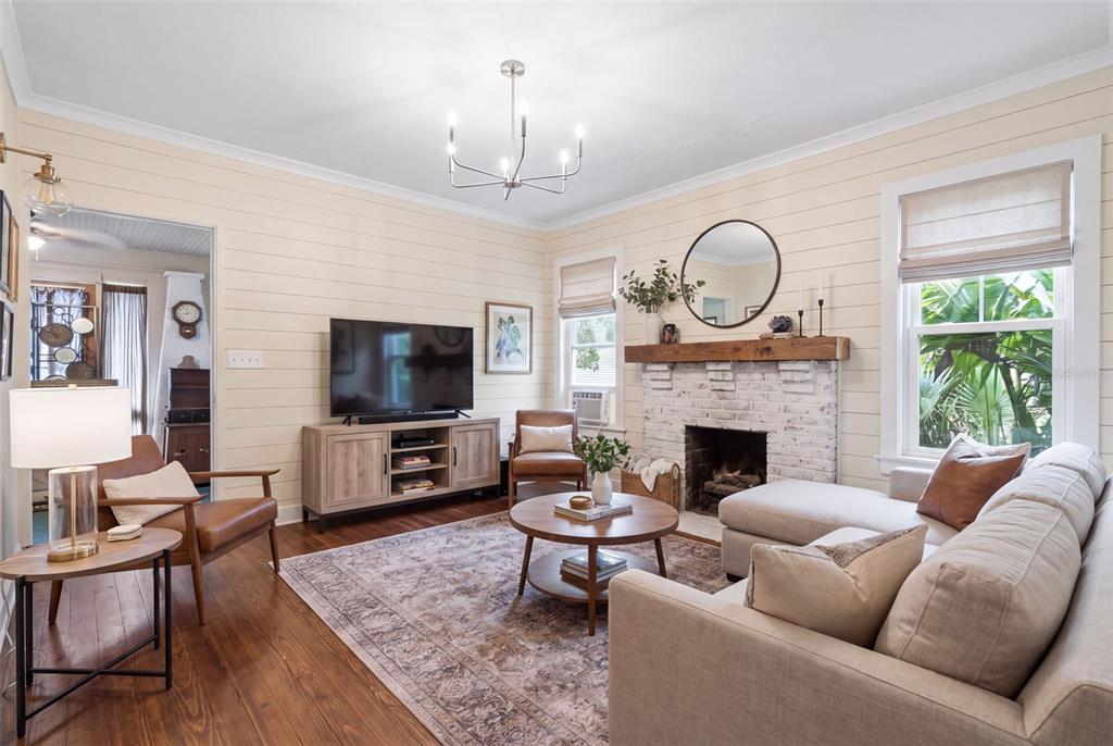 A living room features shiplap walls, a brick fireplace, hardwood floors, and a sectional sofa — 1413 E NEW YORK AVENUE, DELAND, FL