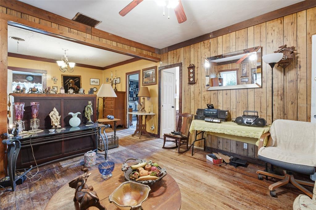 A living room with wood-paneled walls, a wooden floor, and a variety of vintage decor — 1413 E NEW YORK AVENUE, DELAND, FL