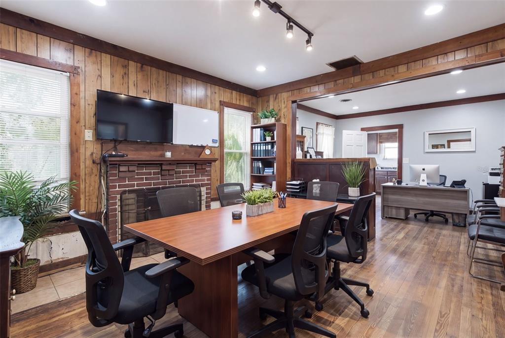 A conference room features wood-paneled walls, a brick fireplace, a central table, and office chairs — 1413 E NEW YORK AVENUE, DELAND, FL