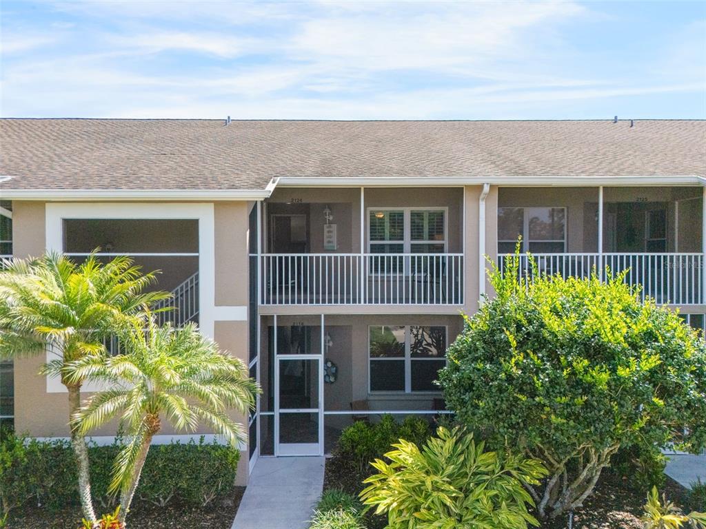 An exterior view of a two-story apartment building with screened balconies and lush landscaping — 5310 HYLAND HILLS AVENUE UNIT 2124, SARASOTA, FL