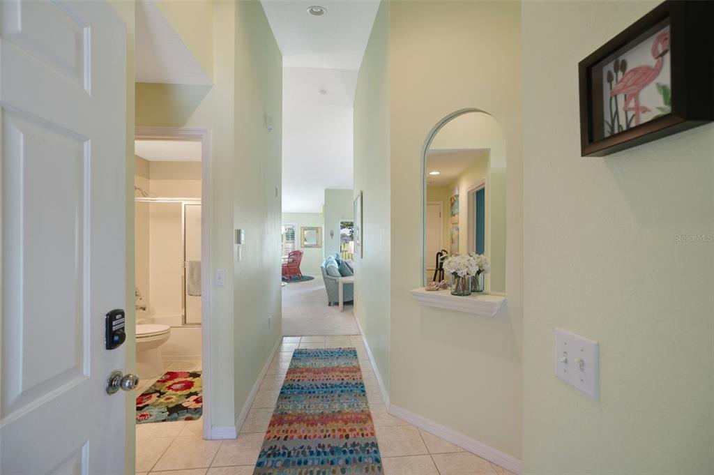 A tiled entryway leads to a living area, featuring a wall niche with a mirror — 5310 HYLAND HILLS AVENUE UNIT 2124, SARASOTA, FL